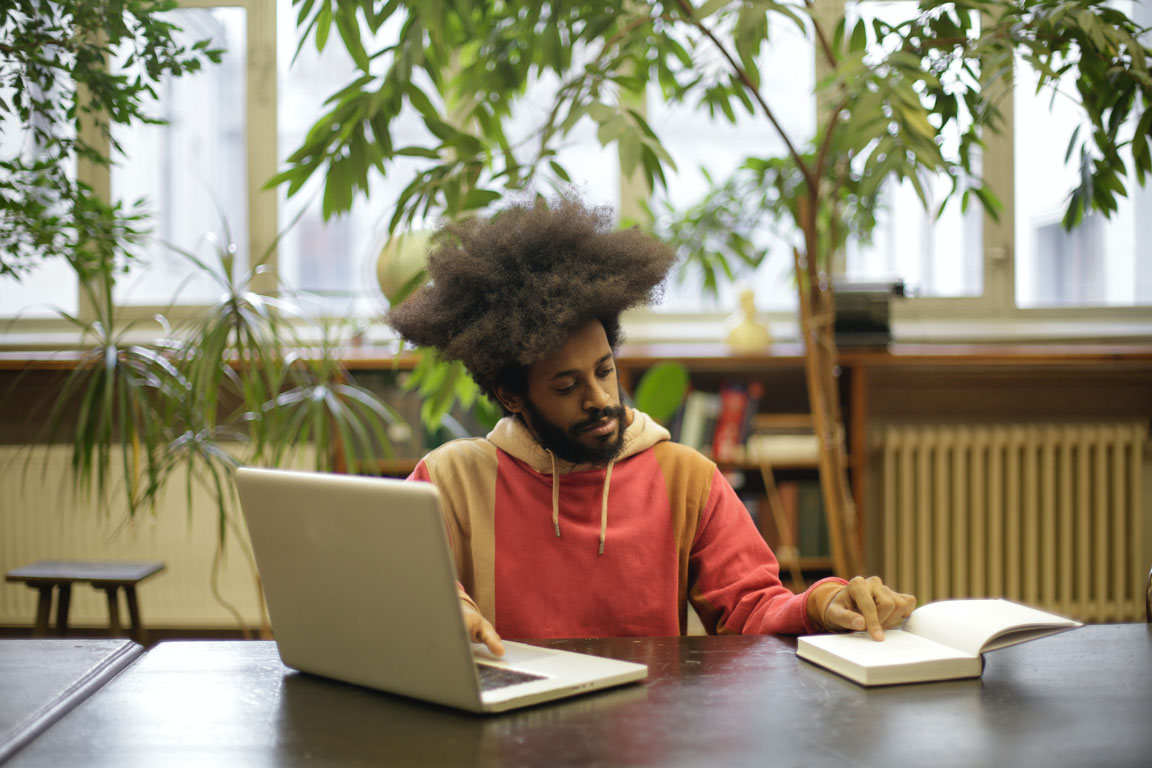 man-using-his-laptop-and-book-for-research-3966557_web