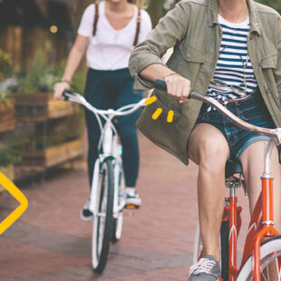 Drei Studierende fahren mit dem Fahrrad in kurzer Hose durch die Stadt