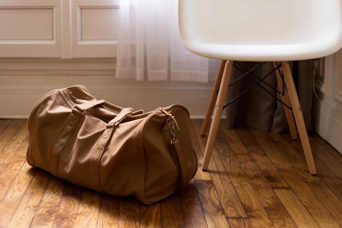 Eine kleine braune Reisetasche liegt auf dem Fußboden eines Zimmers.