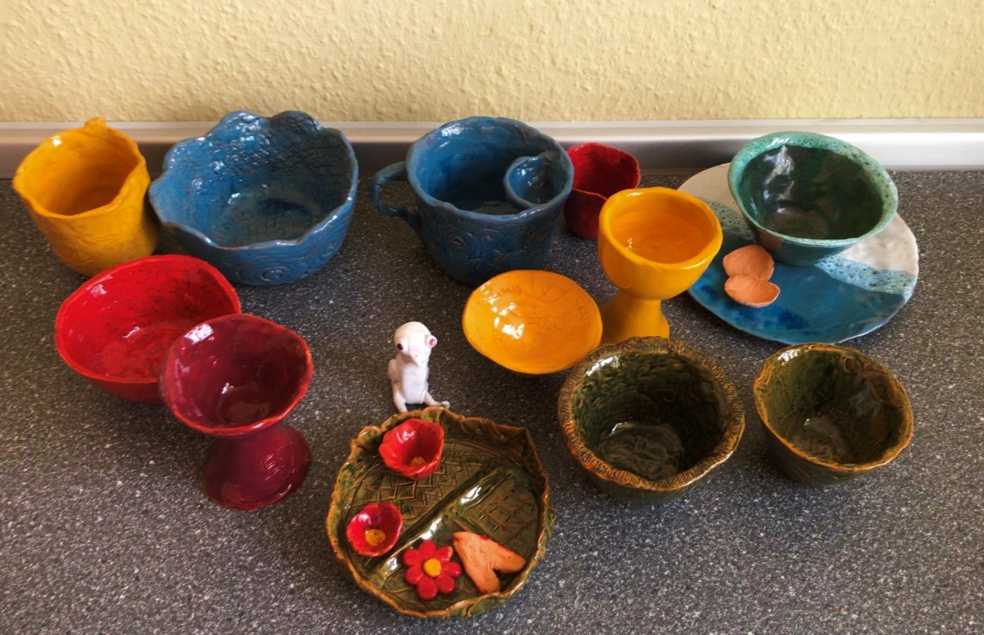 Bunte Keramikschüsseln und Schalen auf einem Tisch.