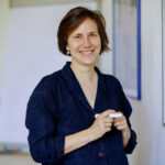 Portrait von Katja Heilmann, sie steht mit einem Stift in der Hand vor einem Whiteboard.