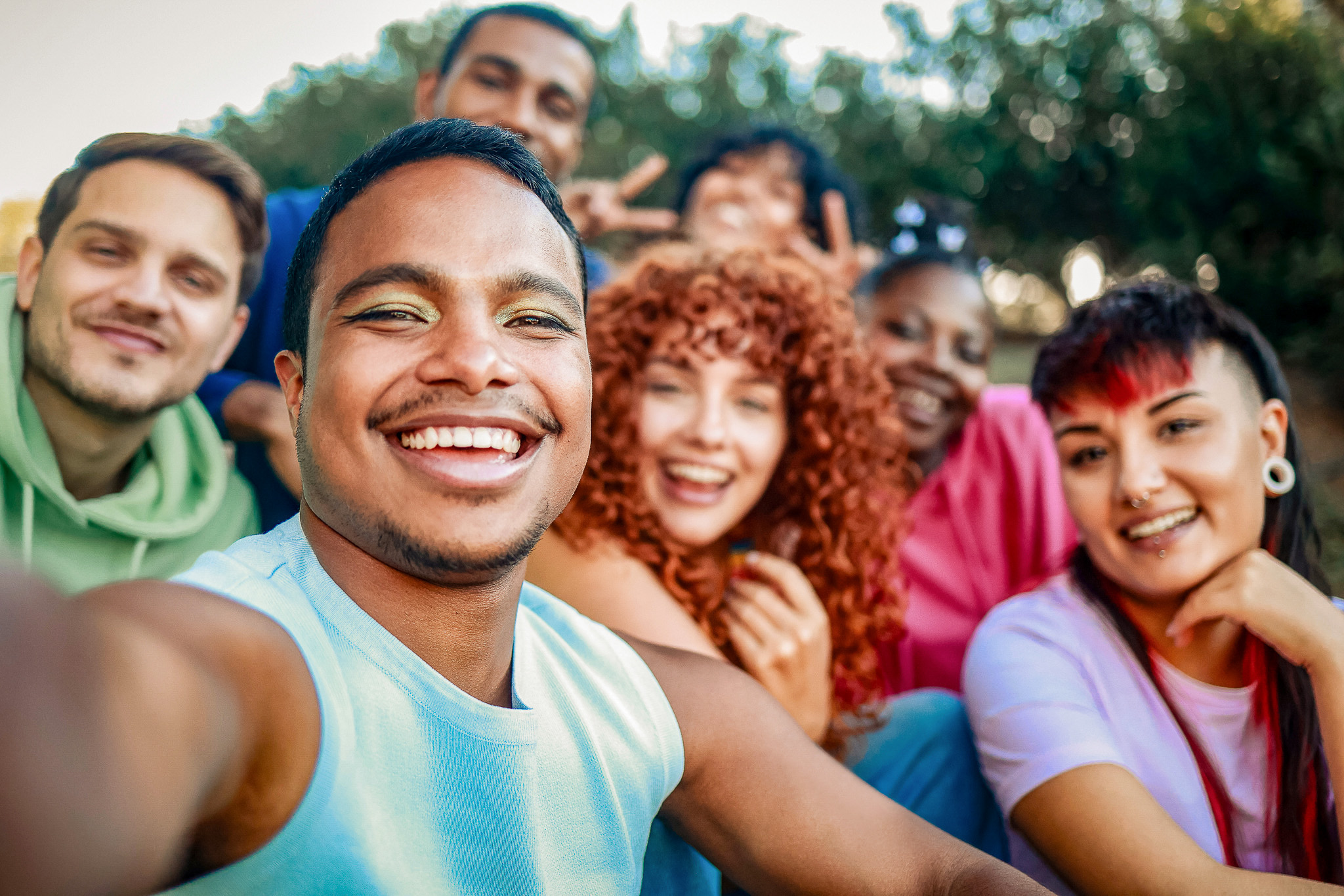 Eine Gruppe junger, fröhlicher Menschen macht gemeinsam ein Selfie im Freien.