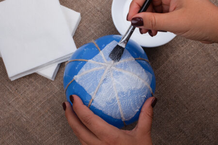the process of gluing napkins on a balloon, creating a pumpkin from papier mache.