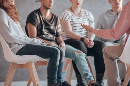 Eine Gruppe Menschen sitzt auf Stühlen im Kreis, man erkennt keine Gesichter.