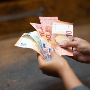 Nahaufnahme von zwei Händen, die mehrere Geldscheine halten