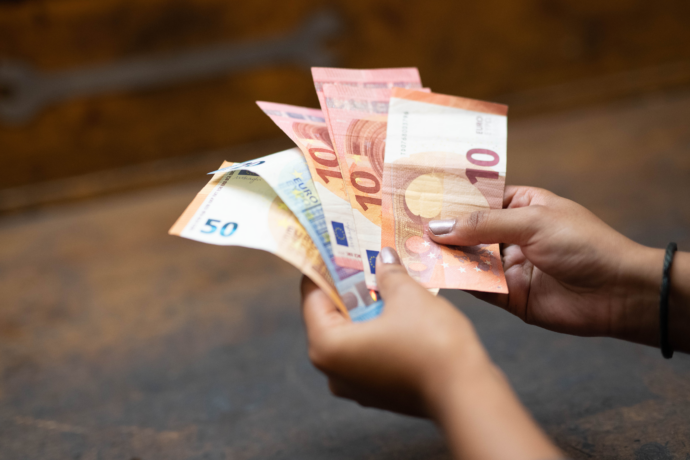 Nahaufnahme von zwei Händen, die mehrere Geldscheine halten