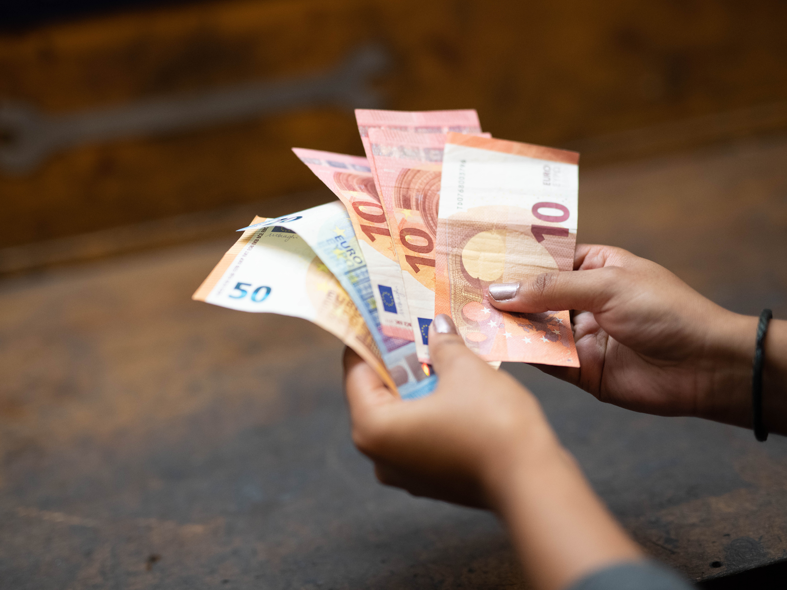 Nahaufnahme von zwei Händen, die mehrere Geldscheine halten