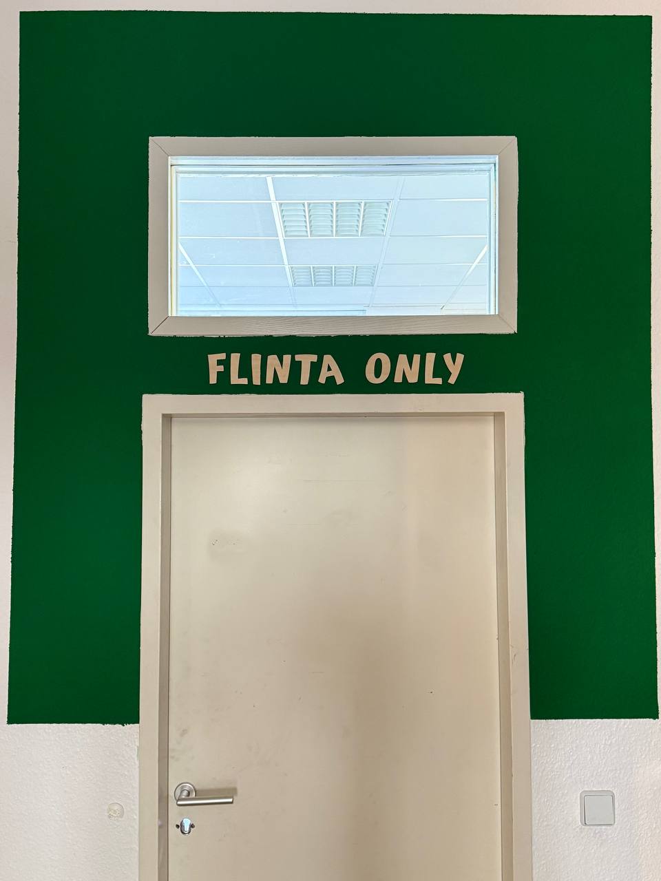 Zu sehen ist eine geschlossene Tür, über der steht "Flinta only"