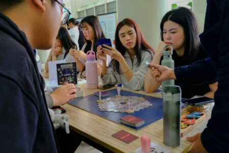 Internationale Studierende sitzen an einem Tisch und spielen verschiedene Gesellschaftsspiele