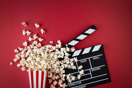 Kino Filmklappe und Popcorn auf rotem Hintergrund