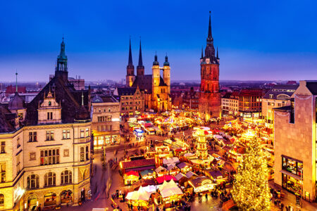 Weihnachtsmarkt in Halle (Saale). Blick auf den weihnachtlich erleuchteten Marktplatz am Abend mit Ständen, Weihnachtsbaum und historischen Gebäuden der Stadt Halle